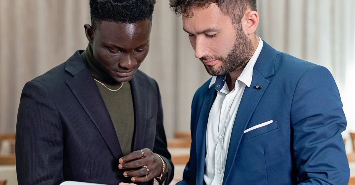 Deux hommes d'affaires en costume examinent un contrat à l'intérieur, se concentrant sur le document.